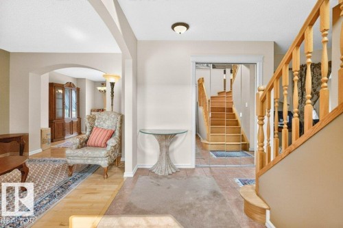 Entrance foyer featuring light wood-finish flooring, a wood staircase with turned balusters, and a neutral color palette - 572 Byrne Crescent, Edmonton, AB 