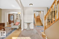 Entrance foyer featuring light wood-finish flooring, a wood staircase with turned balusters, and a neutral color palette - 