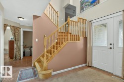 Entryway featuring a wood staircase with balusters and a double-door entry with decorative glass inserts - 