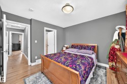 Bedroom featuring hardwood-finish flooring, neutral gray wall tones, and white trim - 