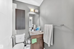 Bathroom featuring a vanity with a stone-finish countertop, wood-finish cabinetry, a wall-mounted mirror, and overhead lighting - 