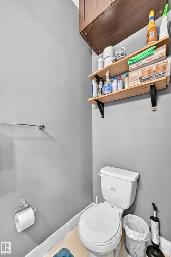 White toilet with wood-finish flooring, light gray walls, and white base trim - 37 13003 132 Avenue Nw, Edmonton, AB 