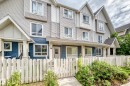 Multi-story townhome exterior featuring light gray horizontal siding, dark blue accent siding, white trim, and a white picket fence - 37 13003 132 Avenue Nw, Edmonton, AB 