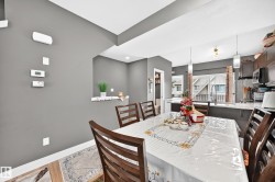 Open-concept dining area featuring wood-finish flooring, a pass-through window, and contemporary pendant lighting - 