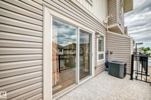 Private balcony featuring a sliding glass door entry, exterior wall lantern, and durable concrete flooring - 37 13003 132 Avenue Nw, Edmonton, AB 