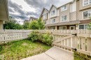 White picket fence enclosing a compact green space with established shrubbery and floral accents - 37 13003 132 Avenue Nw, Edmonton, AB 
