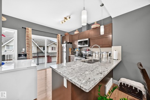 Kitchen with granite countertops, wood-finish cabinetry, and stainless steel appliances - 37 13003 132 Avenue Nw, Edmonton, AB 