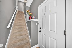 Carpeted staircase with white handrail and trim, alongside a paneled entrance door with dark hardware - 