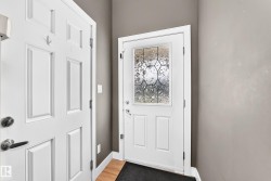 Entryway featuring a white paneled door with decorative leaded glass, wood-finish flooring, and neutral wall paint - 