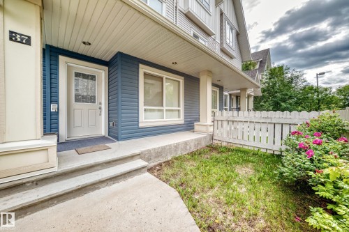 Front entry featuring a white paneled door with decorative glass inserts, concrete steps, and a covered porch - 37 13003 132 Avenue Nw, Edmonton, AB 