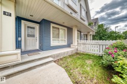 Front entry featuring a white paneled door with decorative glass inserts, concrete steps, and a covered porch - 