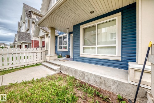 Front exterior featuring blue horizontal siding, a covered porch with supporting columns, and a white picket fence - 37 13003 132 Avenue Nw, Edmonton, AB 