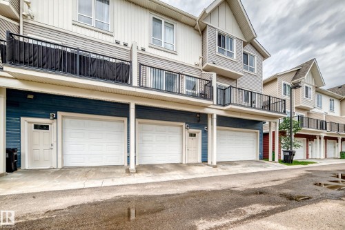 Townhome exterior featuring individual garage access and upper-level balconies with black railings - 37 13003 132 Avenue Nw, Edmonton, AB 