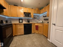 U-shaped kitchen featuring wood cabinetry, integrated black appliances, a built-in microwave, durable countertops, and tiled flooring - 