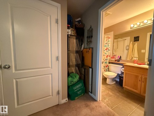 Bathroom with a light wood-finish vanity, a wall-mounted light fixture with four bulbs, and tiled flooring - 205 3425 19 Street, Edmonton, AB 