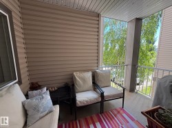Covered balcony featuring neutral-toned siding and a white railing - 