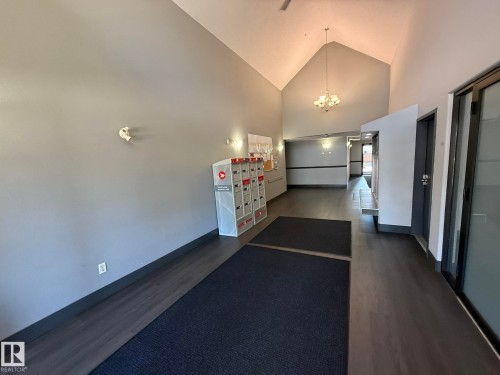 Entryway featuring vaulted ceilings, wood-finish flooring, and a chandelier - 205 3425 19 Street, Edmonton, AB 