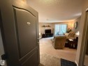 Entryway with tile flooring opening into a carpeted living space featuring a sliding glass door and a wall-mounted shelf - 205 3425 19 Street, Edmonton, AB 
