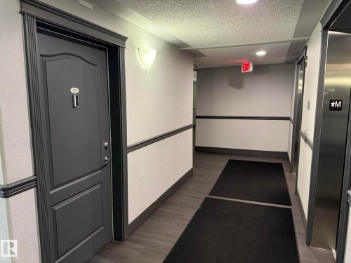 Hallway with wood-finish flooring, two-tone painted walls, and decorative chair rail molding - 205 3425 19 Street, Edmonton, AB 