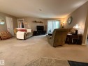 Spacious living area featuring neutral carpeting, light-toned walls, and a sliding glass door leading to an outdoor space - 205 3425 19 Street, Edmonton, AB 