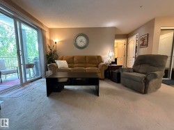 Living area featuring light carpeting and a sliding glass door leading to a private balcony - 