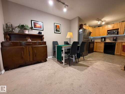 Open-concept living space featuring neutral carpet flooring throughout the main area - 205 3425 19 Street, Edmonton, AB 