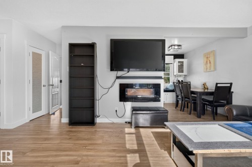 Open concept living area featuring wood-finish flooring, a built-in electric fireplace, and recessed lighting - 7803 73 Street, Edmonton, AB 