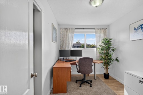 Light-filled room featuring a prominent window, white walls, and wood-finish flooring - 7803 73 Street, Edmonton, AB 