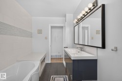 Bathroom featuring a contemporary vanity with an integrated sink, a rectangular framed mirror, and a linear light fixture with multiple bulbs - 