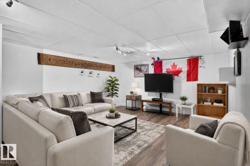 Spacious living area featuring track lighting, wood-finish flooring, and a drop ceiling - 7803 73 Street, Edmonton, AB 