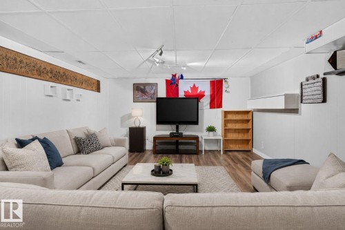 Finished lower level featuring wood-finish flooring, white paneled walls, and a drop ceiling - 7803 73 Street, Edmonton, AB 