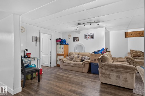 Spacious room with wood-finish flooring, white panel walls, and a white drop ceiling - 7803 73 Street, Edmonton, AB 