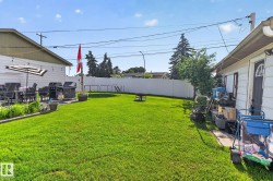 Expansive green lawn backyard featuring a white privacy fence and a rear patio area - 