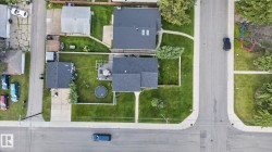 Residential property featuring a dark shingle roof, paved driveway, and established green lawn - 
