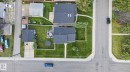 Residential property featuring a dark shingle roof, paved driveway, and established green lawn - 7803 73 Street, Edmonton, AB 