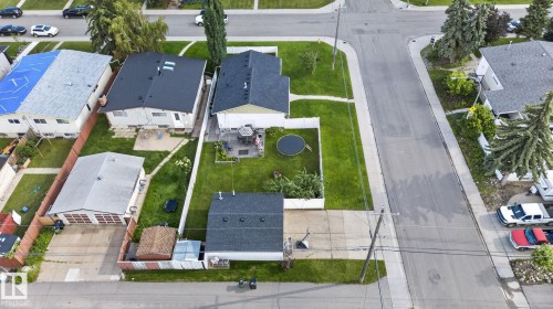 Property featuring a large backyard with a patio, green lawn, and a white privacy fence - 7803 73 Street, Edmonton, AB 
