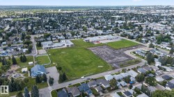 Expansive aerial showcasing a residential community featuring single-family homes, mature trees, green spaces, and community buildings - 