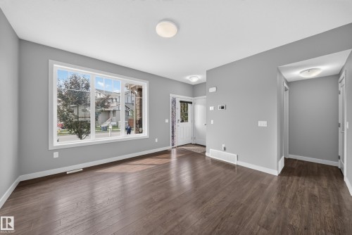 Open concept living area featuring dark wood-finish flooring, a large multi-pane window, and light gray painted walls - 2331 Casey Crescent Sw, Edmonton, AB 