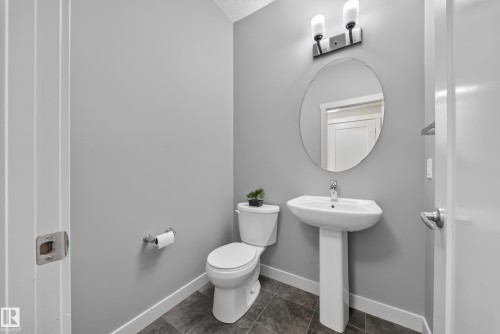 Bathroom featuring a pedestal sink, oval mirror, and tile flooring - 2331 Casey Crescent Sw, Edmonton, AB 