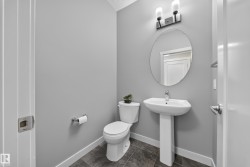 Bathroom featuring a pedestal sink, oval mirror, and tile flooring - 