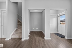 Foyer featuring wood-finish flooring, white trim, and a bright white door with an upper window - 