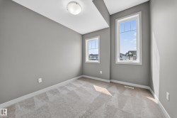 Interior room featuring two vertical windows with white trim, gray painted walls, and light-colored patterned carpet - 