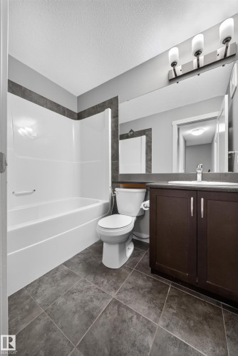 Full bathroom featuring a white tub/shower combination with dark accent tiling - 2331 Casey Crescent Sw, Edmonton, AB 