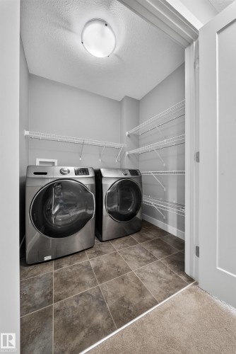 Dedicated laundry area featuring a front-load washer and dryer, tile flooring, and integrated wire shelving for storage - 2331 Casey Crescent Sw, Edmonton, AB 
