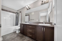 Double vanity with dark wood-finish cabinetry, integrated sinks, and chrome faucets - 