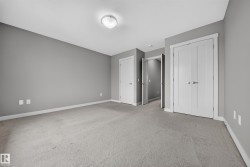 Carpeted room with a flush-mount ceiling light fixture, neutral gray wall paint, white baseboards, and multiple white panel doors - 