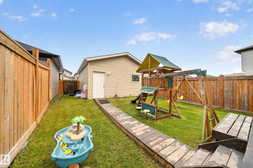 Expansive backyard featuring a manicured lawn, wood fencing, and a detached garage with vinyl siding - 2331 Casey Crescent Sw, Edmonton, AB 