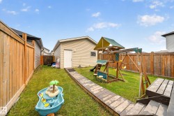 Expansive backyard featuring a manicured lawn, wood fencing, and a detached garage with vinyl siding - 