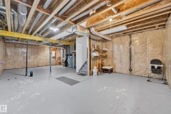 Unfinished basement featuring exposed ceiling joists and utility piping - 