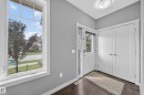 Entryway featuring wood-finish flooring, a white paneled entry door with a clear glass insert, and double bi-fold closet doors with brushed nickel hardware - 2331 Casey Crescent Sw, Edmonton, AB 